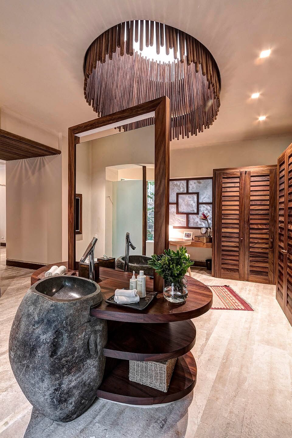 Primary ensuite with a freestanding river-stone basin on a circular walnut vanity, carved wood ceiling medallion, a floor-to-ceiling mirror, and louvered room doors beyond, Casa Escondida, Ranchos Estates, Punta Mita.