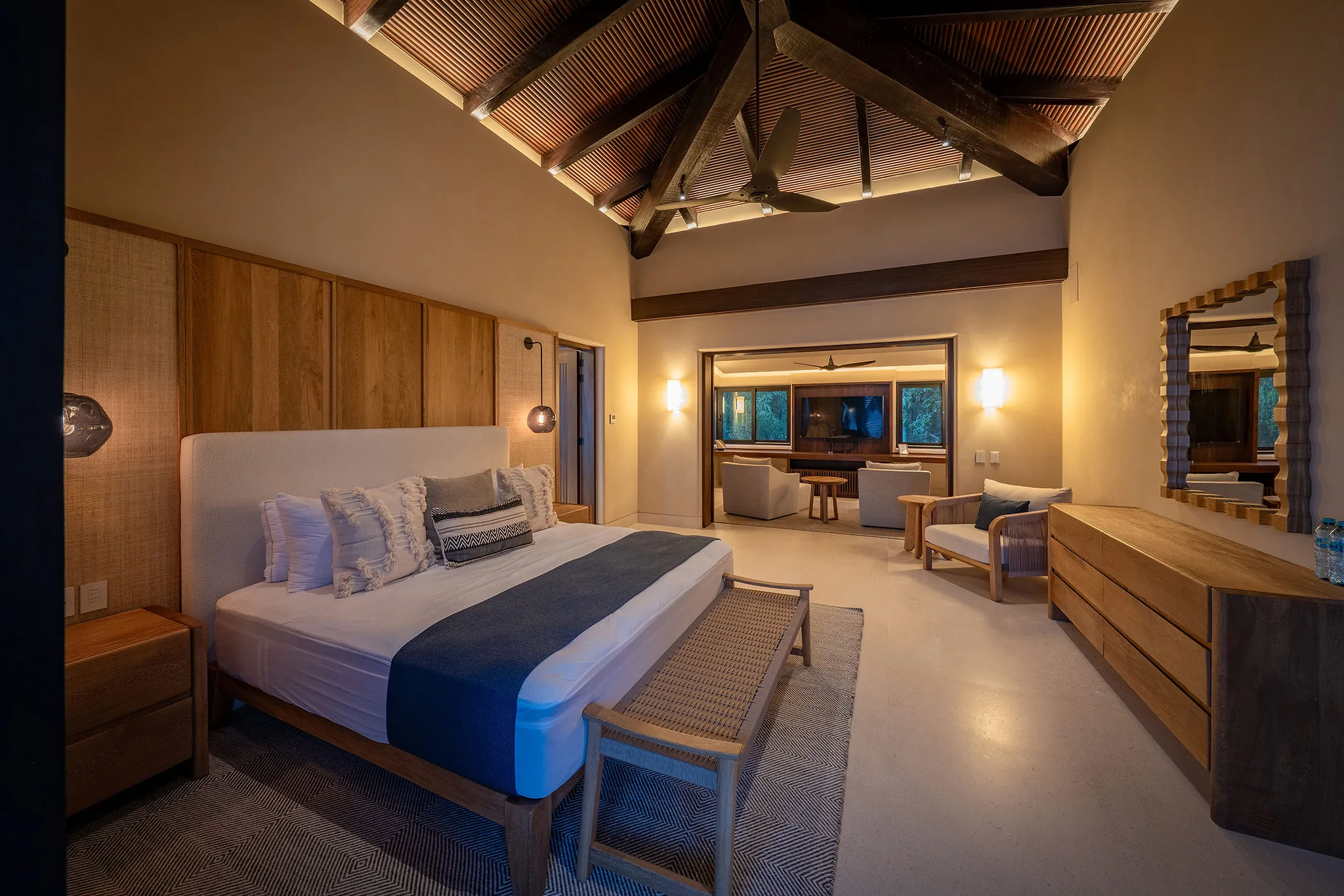 Primary bedroom with vaulted wood-beam ceiling, upholstered king headboard, oak dresser, and sitting area visible through the open doorway, Casa Happy Paws, Ranchos Estates, Punta Mita.