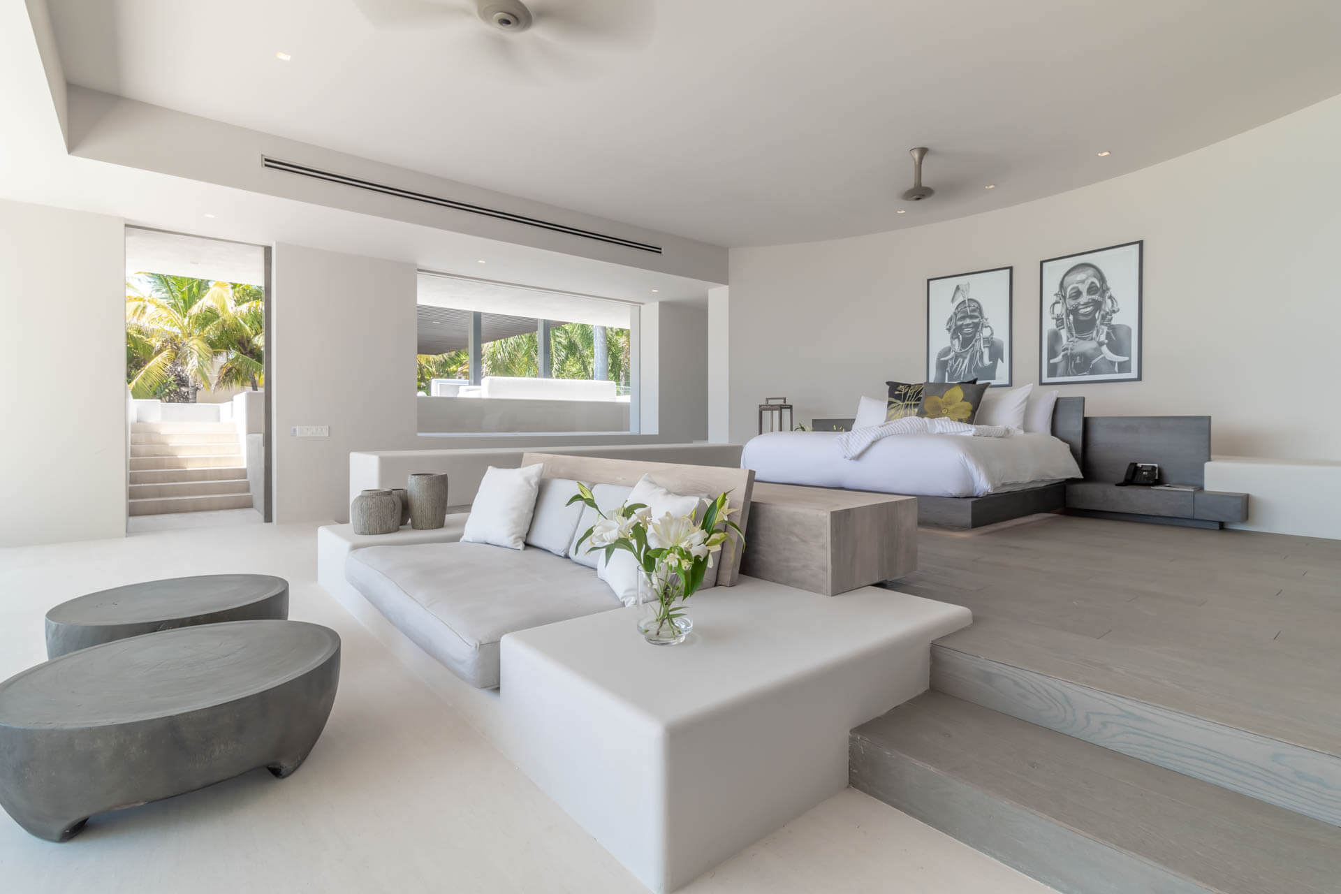 Primary suite sitting area with African portrait prints, stone coffee tables, and raised platform bed, Estate Afrique, Ranchos Estates, Punta Mita.