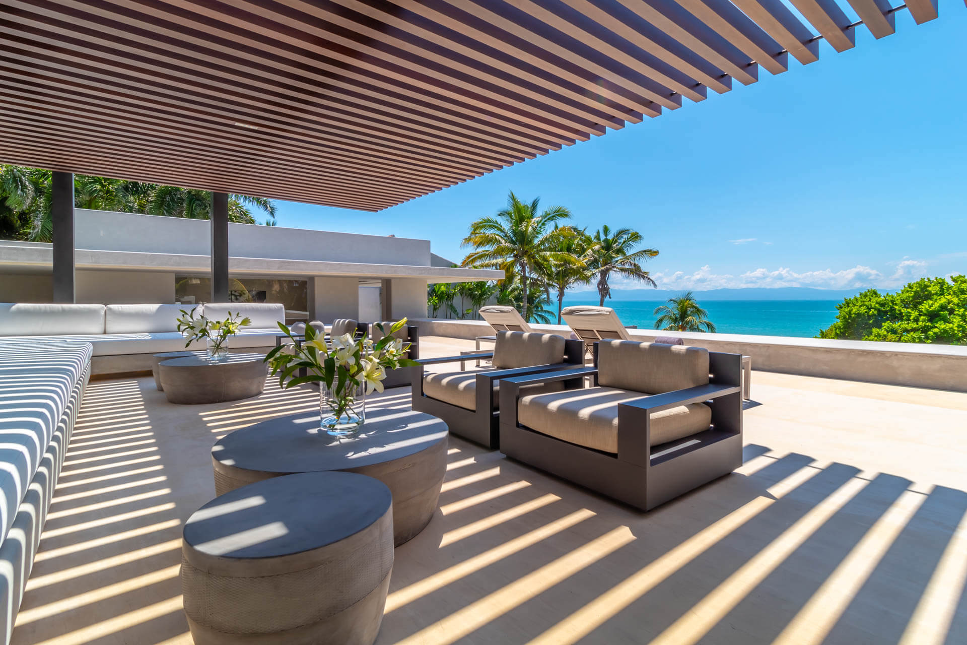 Upper rooftop terrace with dark-frame lounge chairs and striped cushions facing the Pacific, Estate Afrique, Ranchos Estates, Punta Mita.