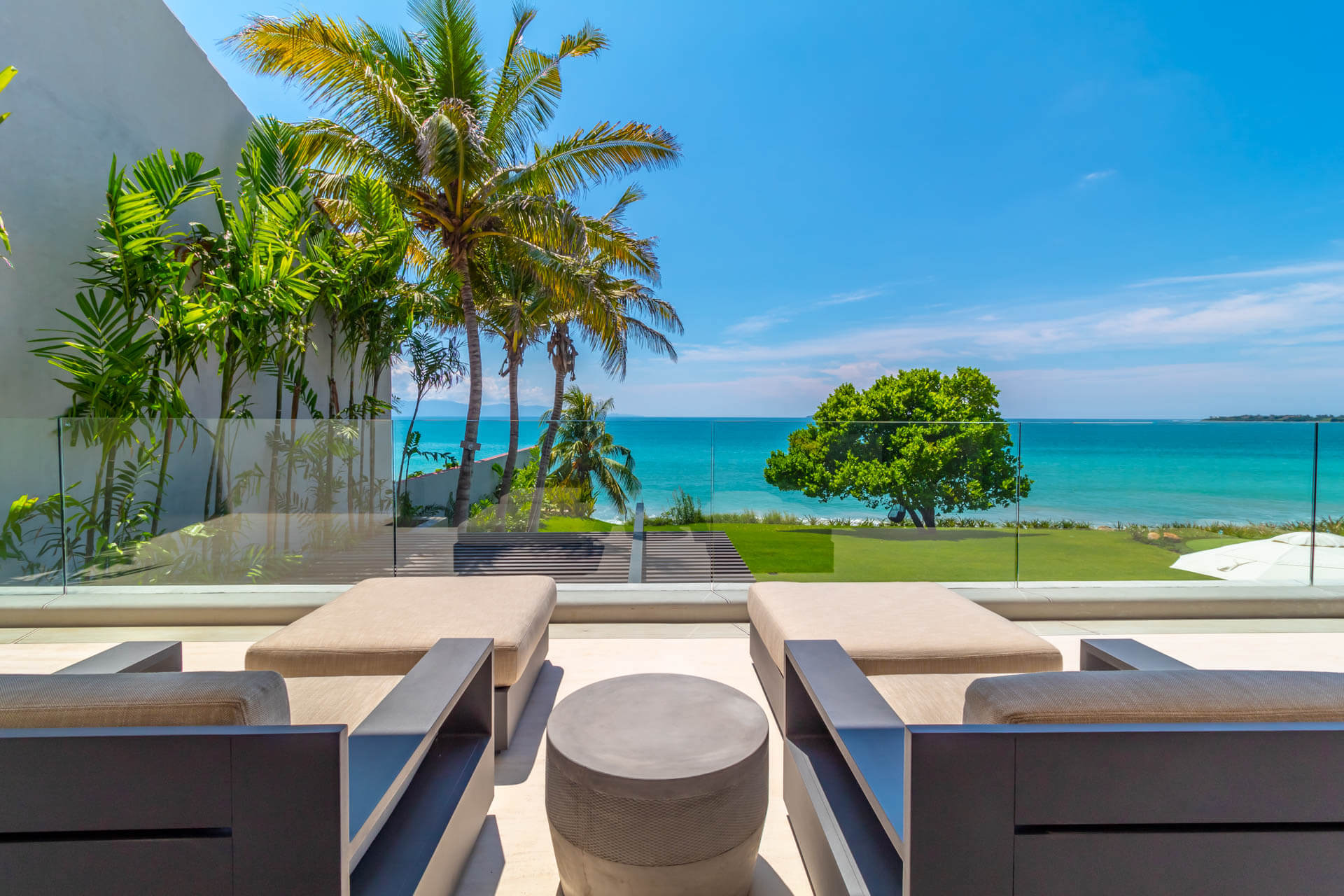 Upper terrace day-beds with glass railing overlooking turquoise ocean and palms, Estate Afrique, Ranchos Estates, Punta Mita.