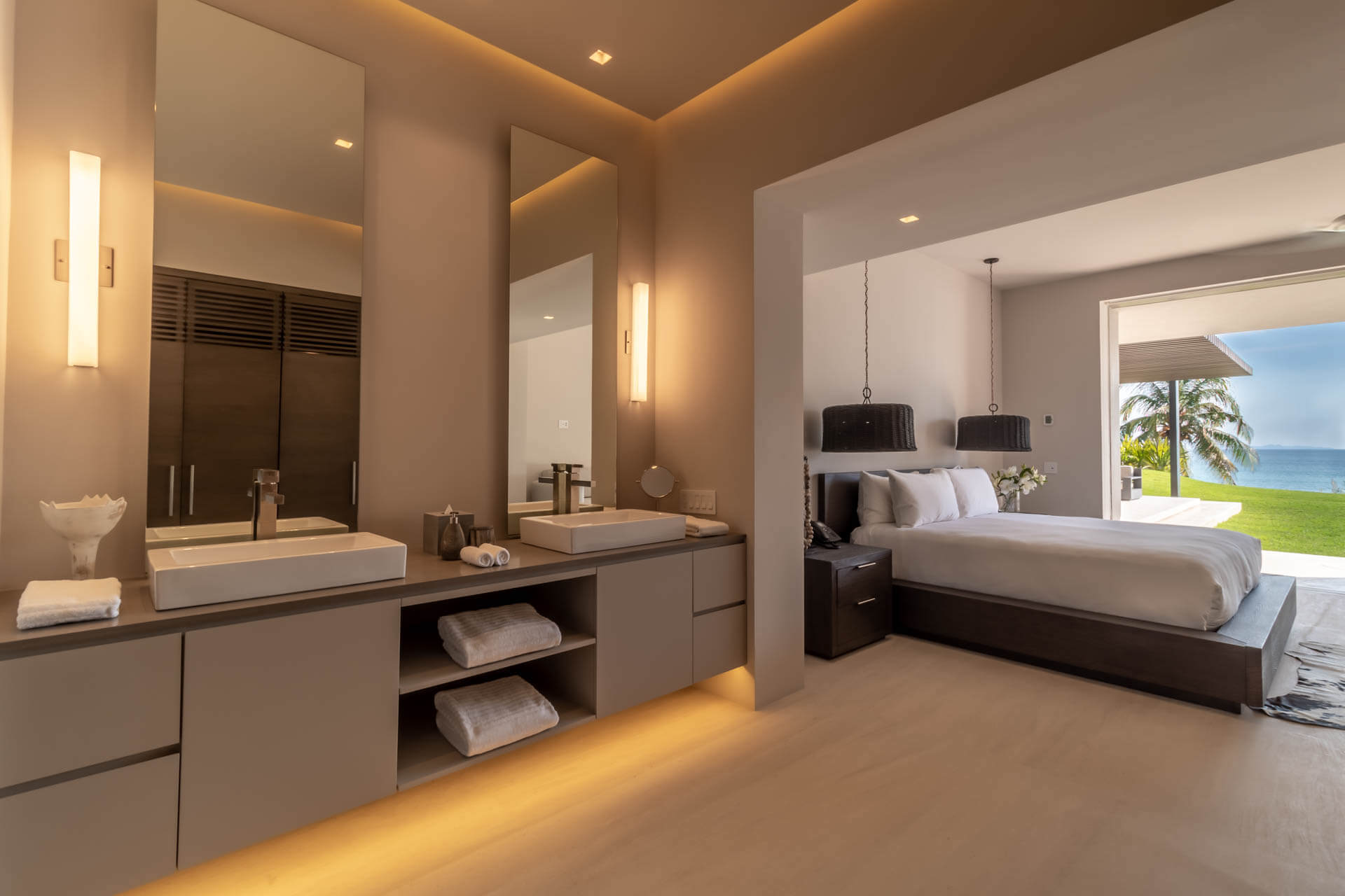 Guest suite open-plan double vanity with warm lighting leading to king bedroom and ocean view beyond sliding doors, Estate Afrique, Ranchos Estates, Punta Mita.