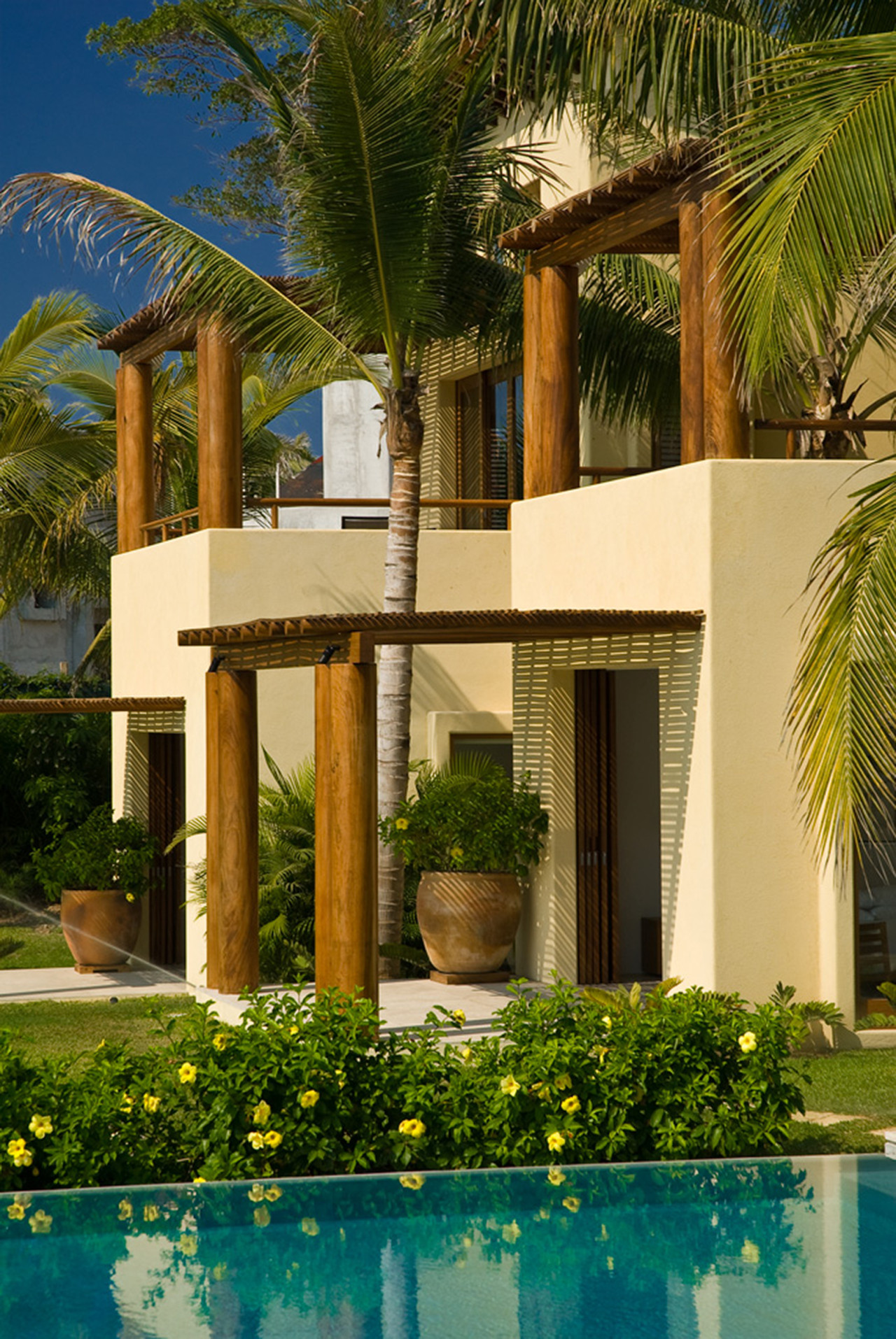 Two-story cream stucco facade with wood-column pergola and bougainvillea garden, Estate Jaguar, Ranchos Estates, Punta Mita.