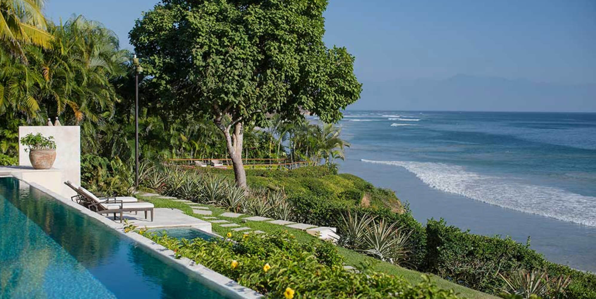 Infinity pool edge with sun loungers alongside tropical gardens descending to the private beach and the Pacific, Estate Jaguar, Ranchos Estates, Punta Mita.