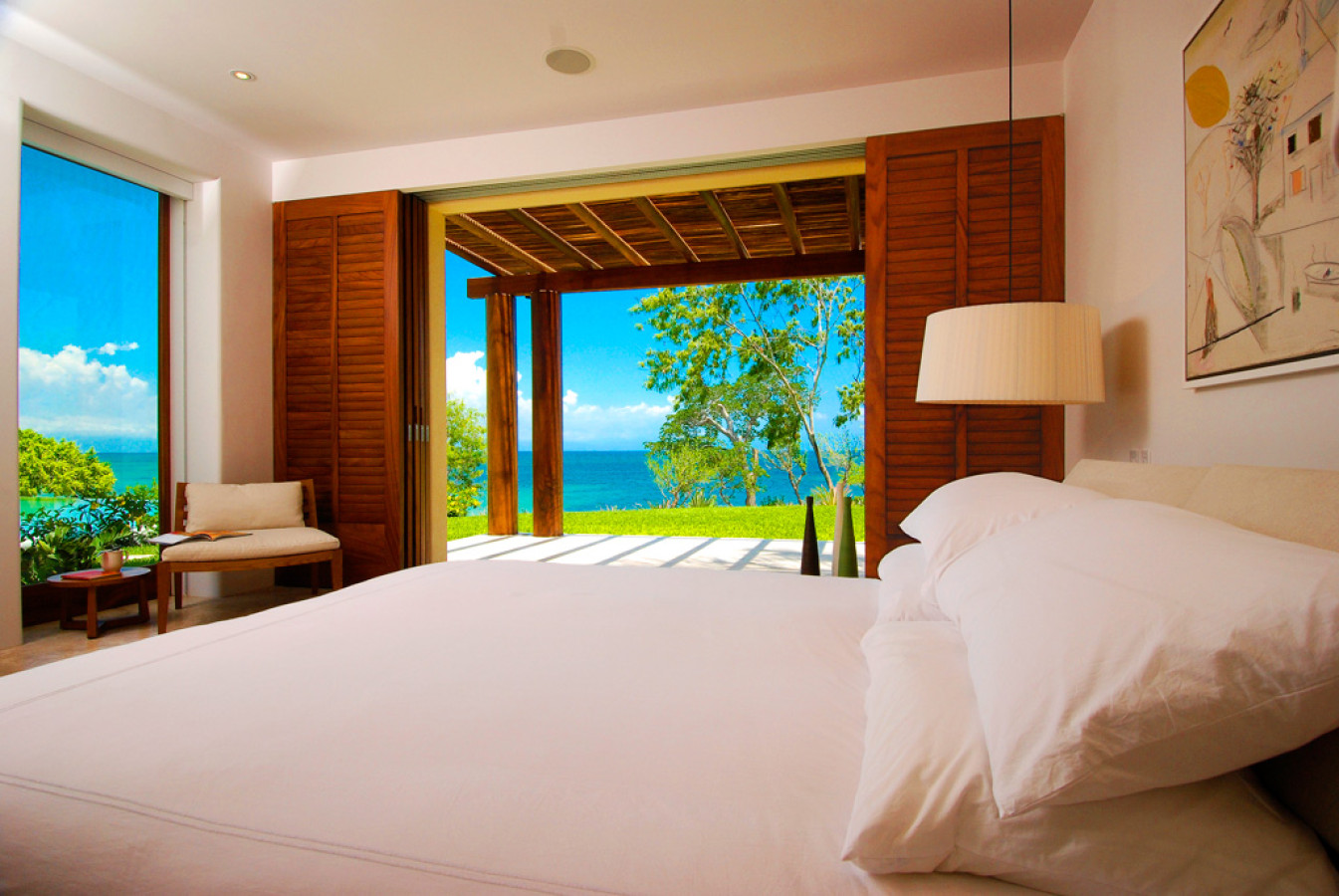 Guest bedroom with white king bed, louvered wood shutters folded back, and an unobstructed ocean view through the open terrace, Estate Jaguar, Ranchos Estates, Punta Mita.