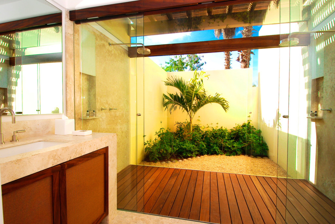 Open-sky shower with glass enclosure, teak decking, and a private tropical garden courtyard, travertine vanity at left, Estate Jaguar, Ranchos Estates, Punta Mita.