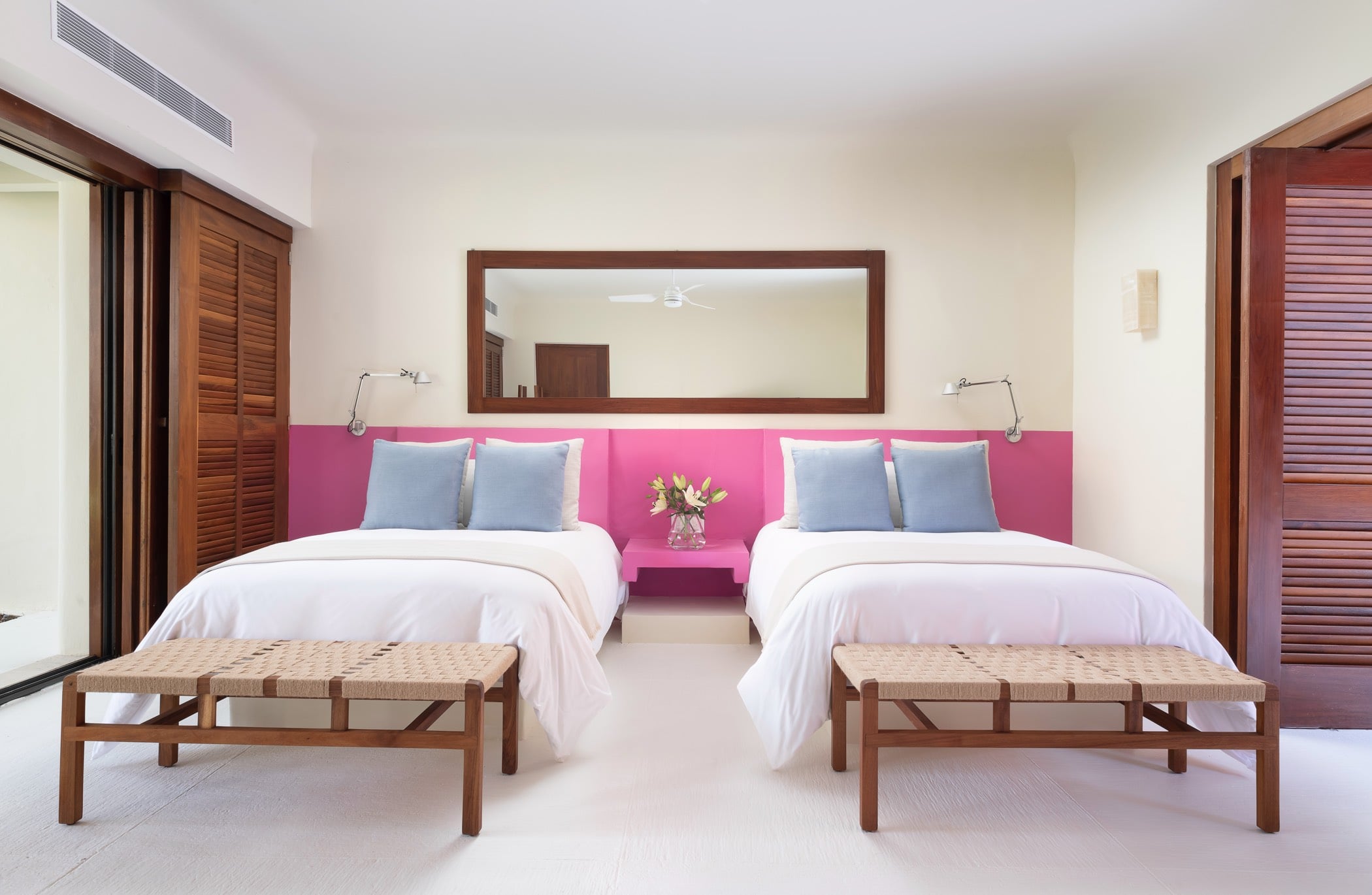 Guest suite with two queen beds, hot-pink headboard band, slate-blue pillows, and full-length mirror, Villa Pacífica, Ranchos Estates, Punta Mita.