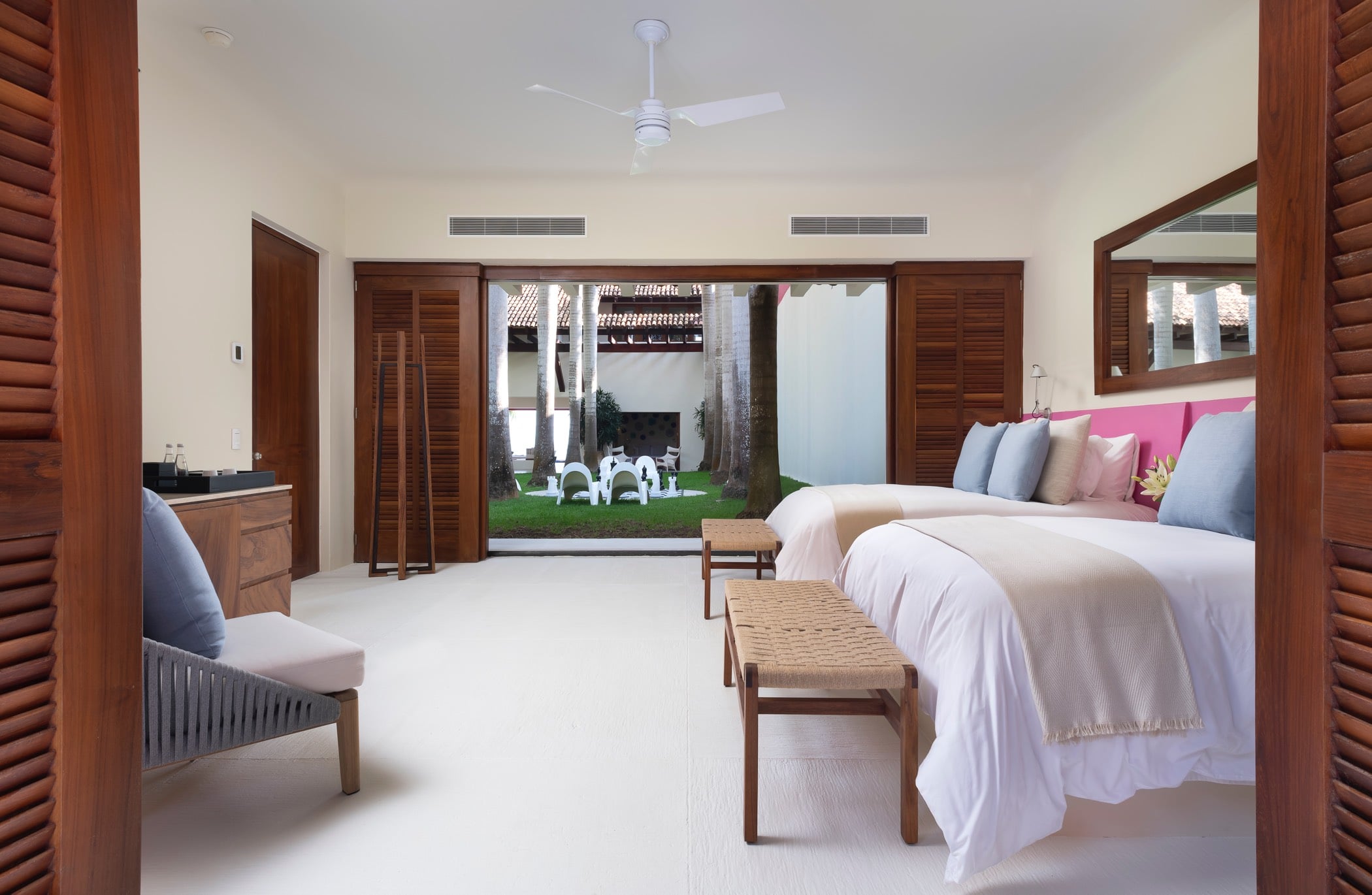 Guest suite with two queen beds, pink headboard accent, louvered doors open to an interior garden, Villa Pacífica, Ranchos Estates, Punta Mita.