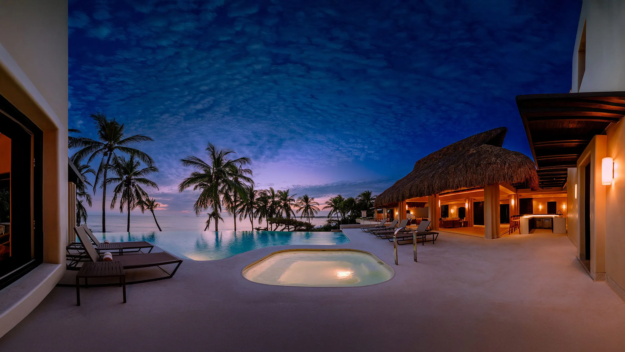 Casa Happy Paws, a luxury Punta Mita beachfront villa in Ranchos Estates, glows at dusk with palm trees and infinity pool.