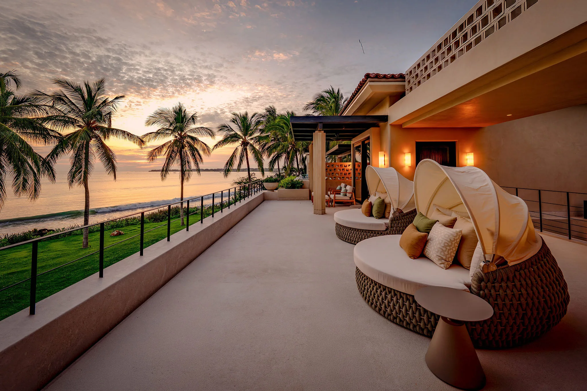 Spacious Casa Happy Paws terrace at Ranchos Estates, Punta Mita with lounge chairs, sunset lawn, palms, and ocean views.