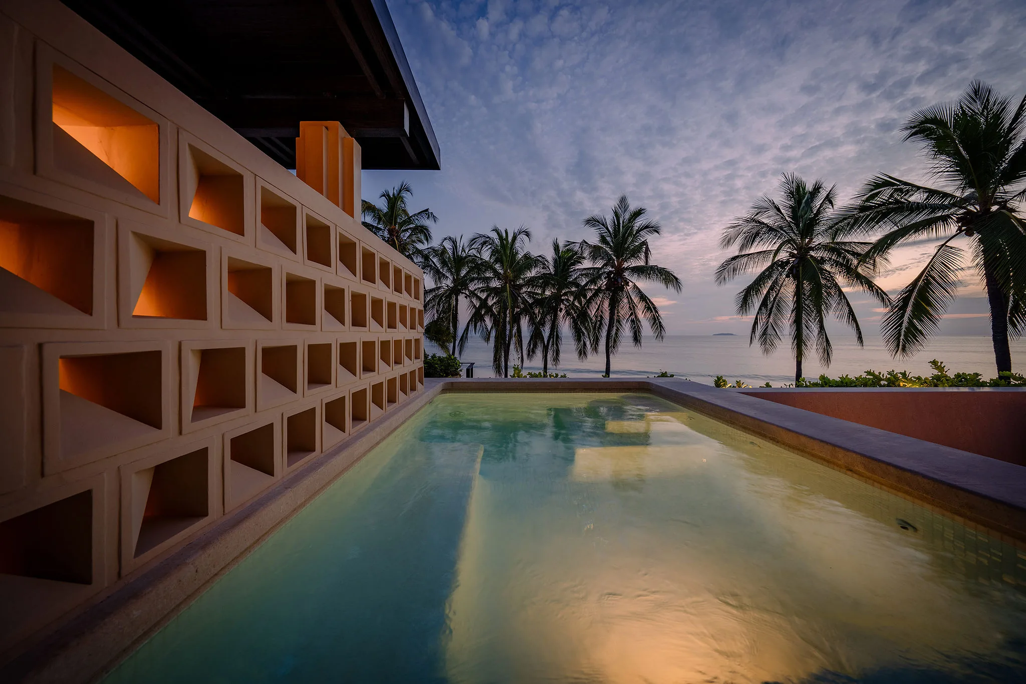Casa Happy Paws’ tranquil pool, glowing lights, palm trees, and ocean views at sunset in Punta Mita’s Ranchos Estates.