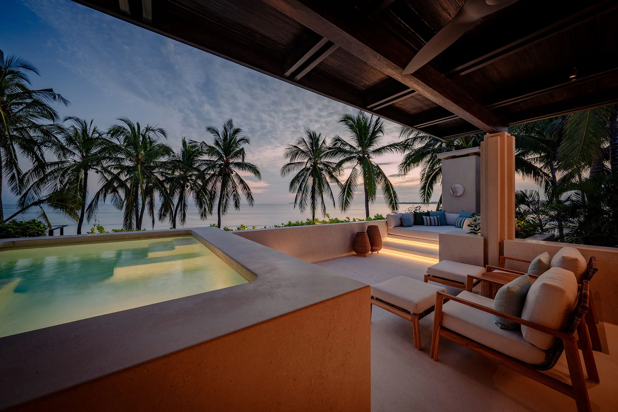 Luxurious patio at Casa Happy Paws, Ranchos Estates, Punta Mita: lounge chairs, pool, palms, and ocean sunset views.