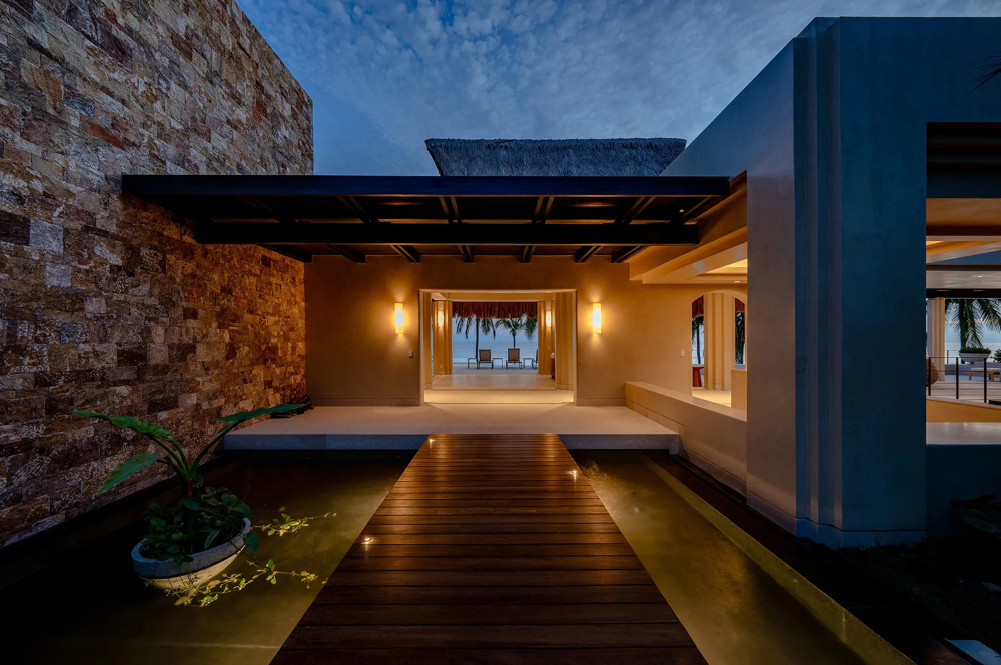 Modern villa entrance at dusk in Punta Mita’s Ranchos Estates, Casa Happy Paws opens to beach views and palm trees.