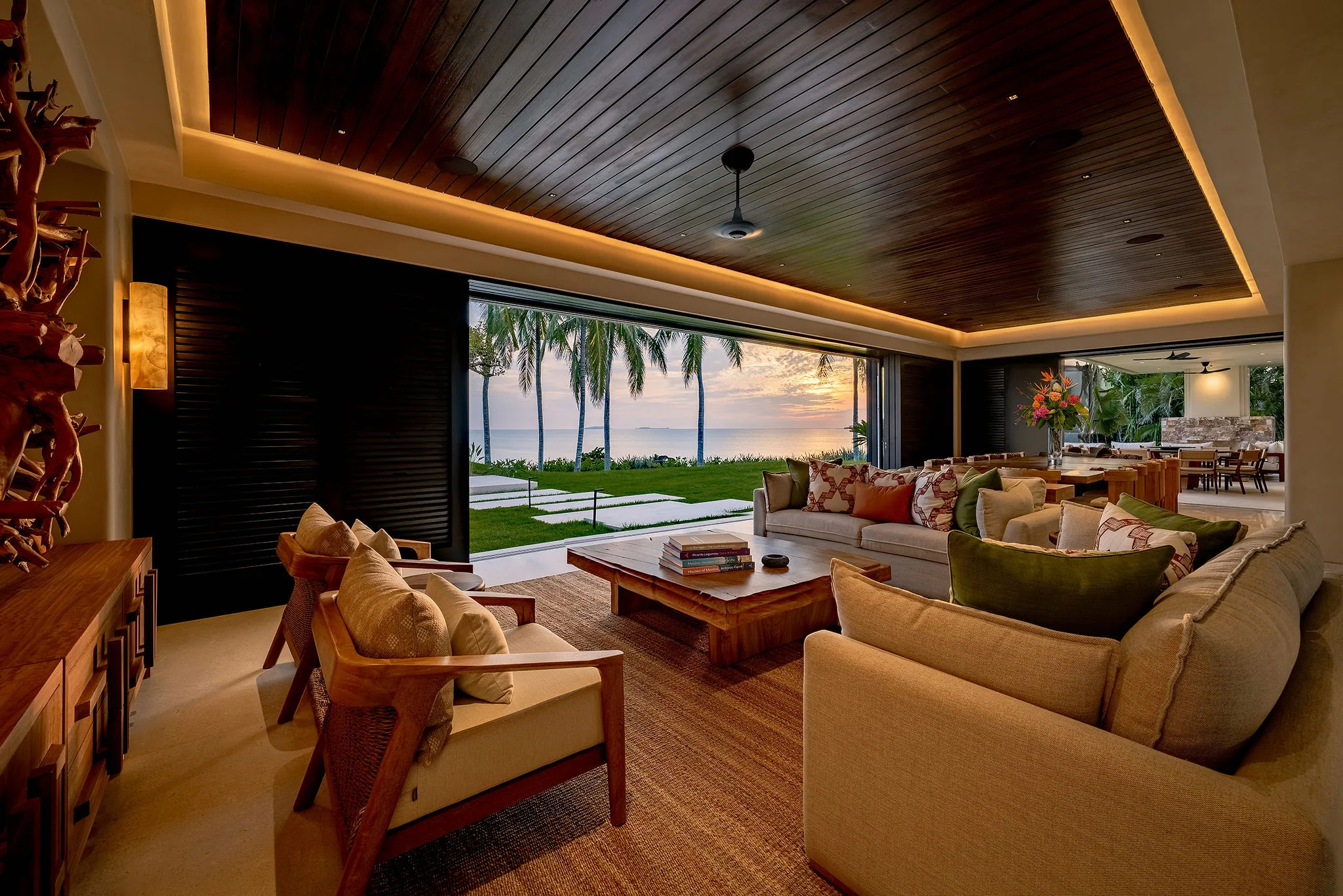Modern open living room at Casa Happy Paws, Ranchos Estates, Punta Mita, with ocean sunset views and palm-lined patio.