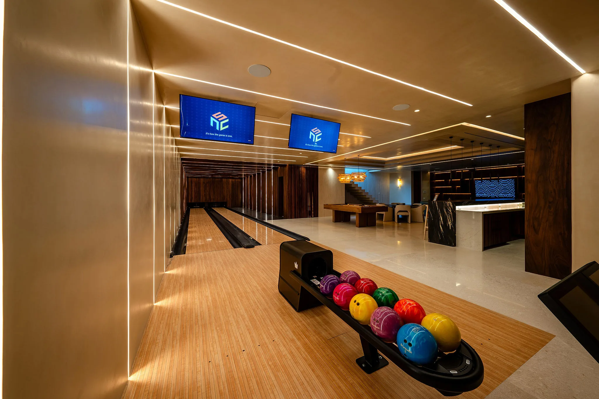 Luxury Punta Mita Ranchos Estates game room with two-lane bowling, pool table, kitchen bar, and vibrant lighting.
