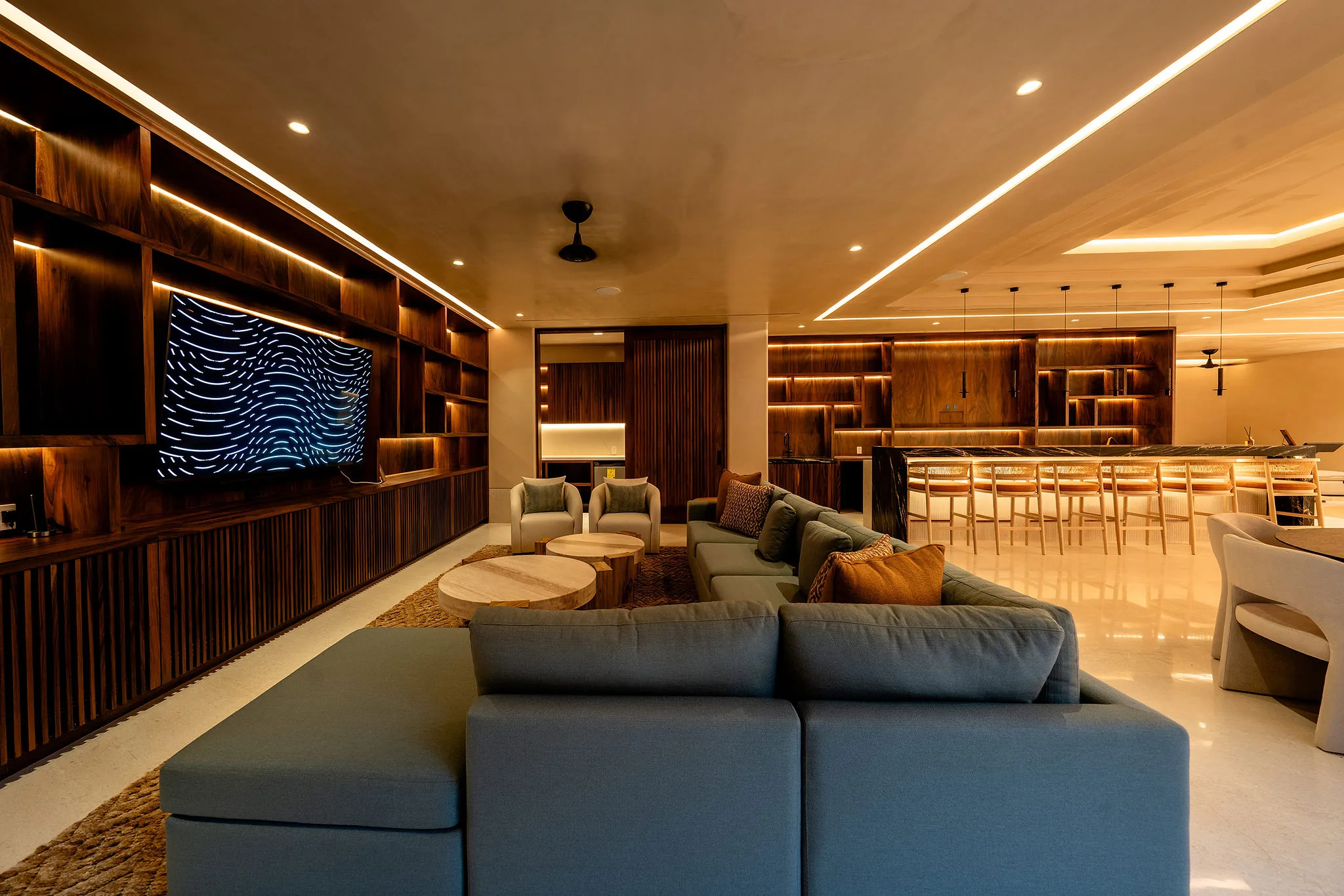 Chic Punta Mita living room and kitchen with wood accents, sectional sofa, bar stools, and TV at Ranchos Estates.