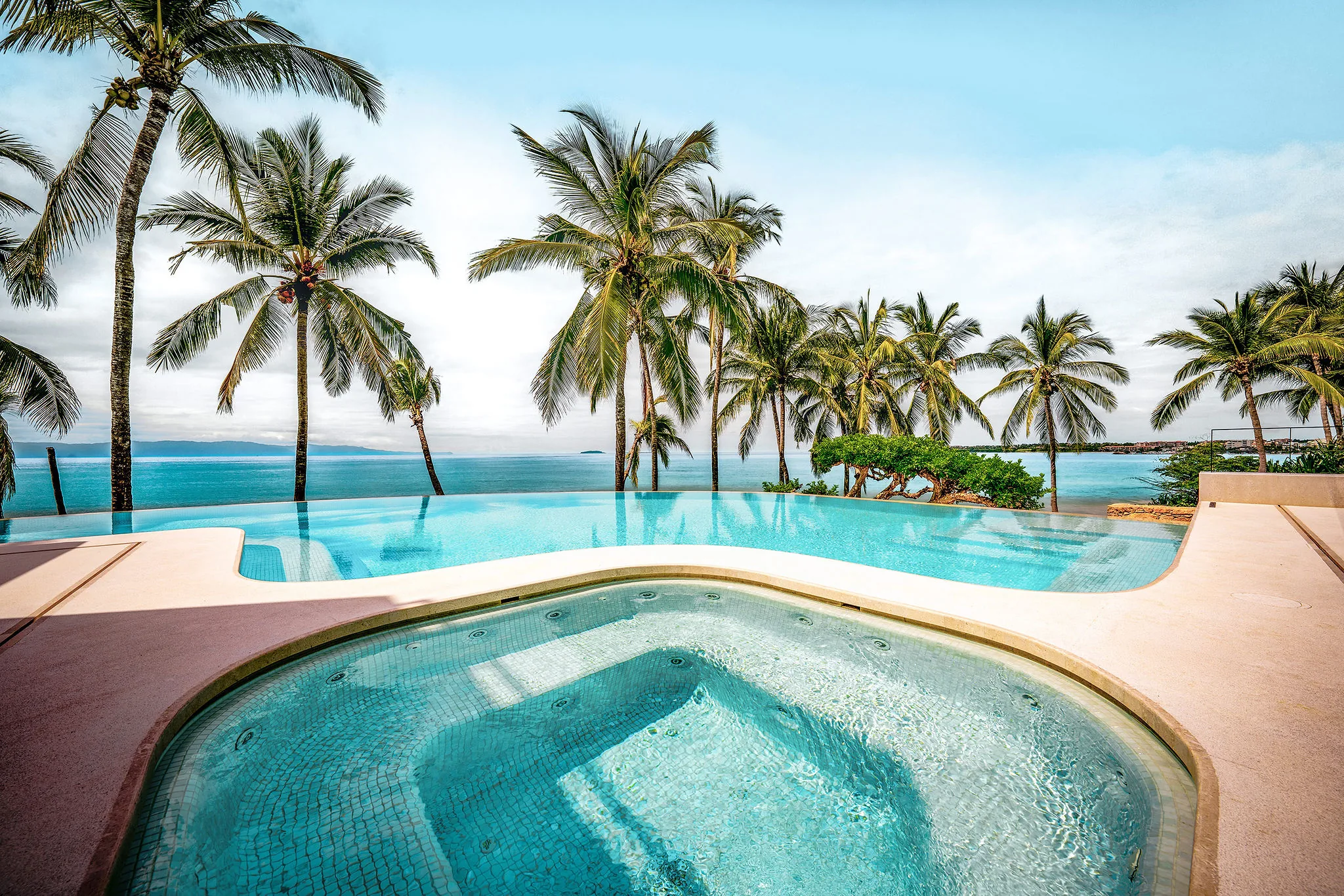 Infinity pool and hot tub at Casa Happy Paws, Ranchos Estates, Punta Mita, overlook palm-lined beach and blue ocean.