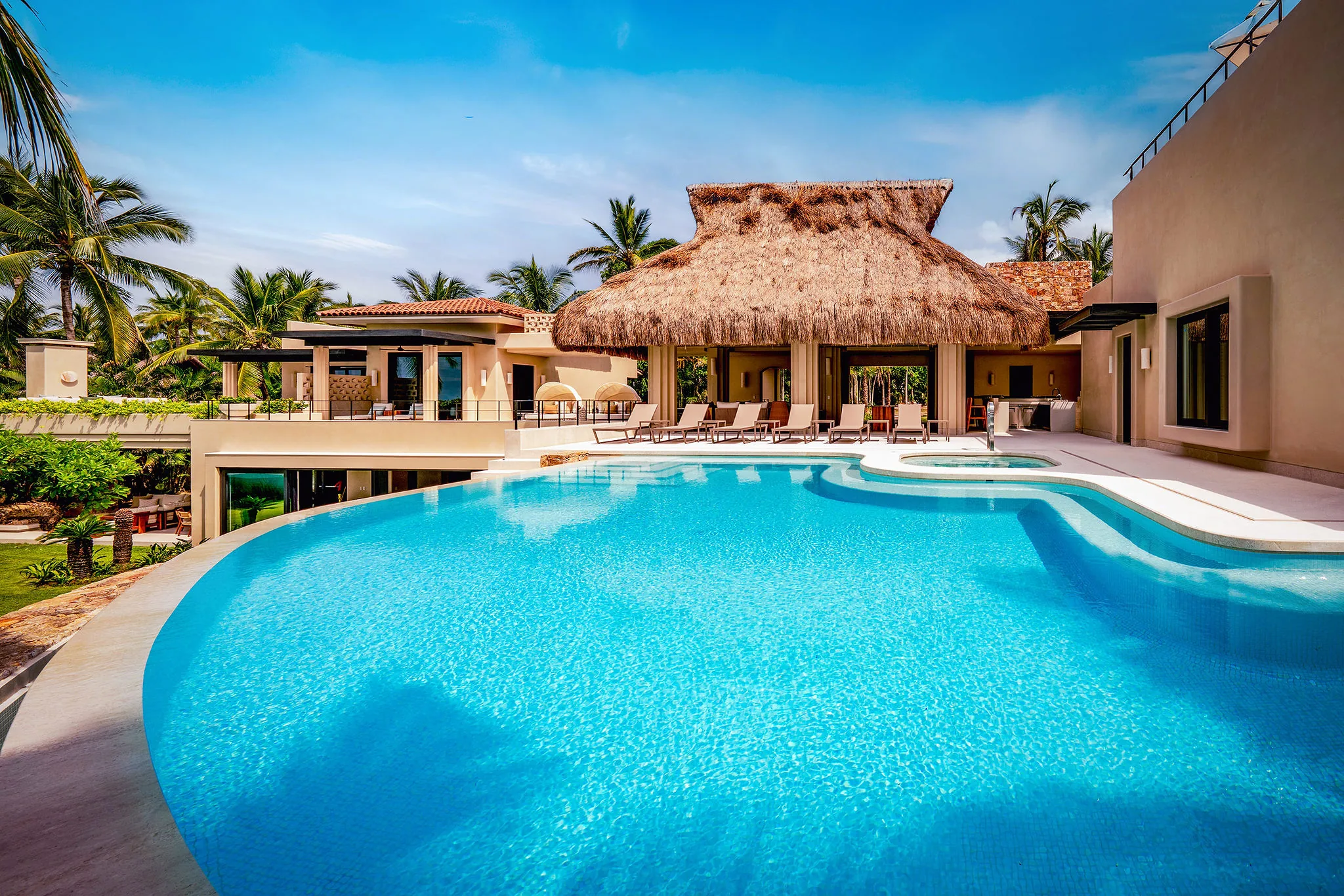 Casa Happy Paws in Punta Mita, Ranchos Estates: tropical villa, large curving pool, loungers, palms, thatched cabana.