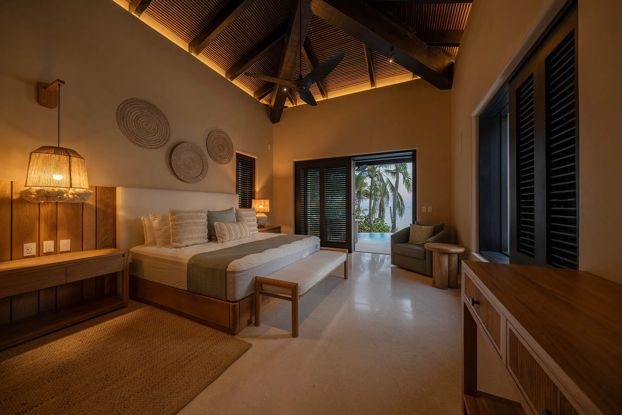 Modern bedroom at Casa Happy Paws, Punta Mita: wood furniture, woven decor, palm views, exposed beams, cozy seating.