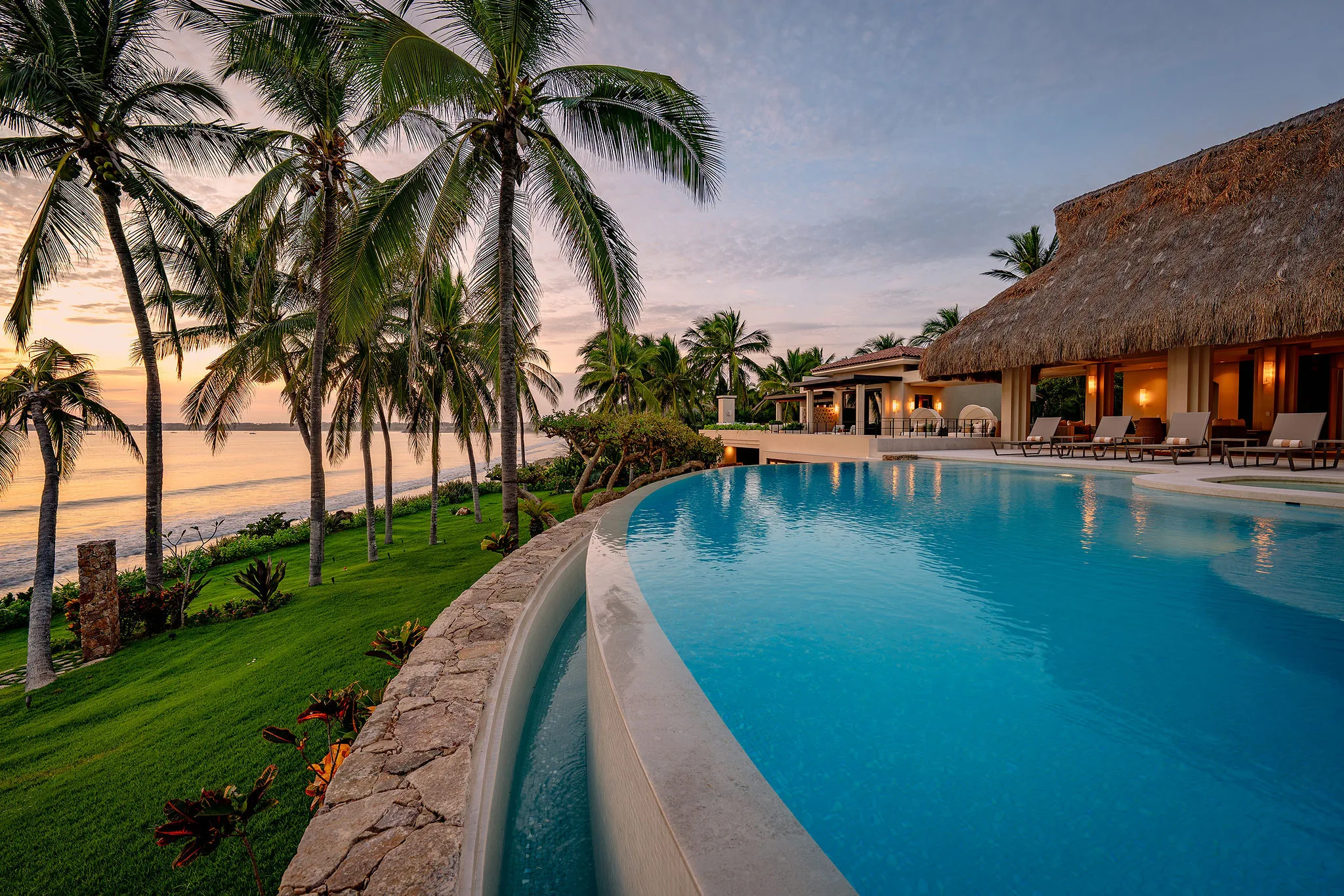 Infinity pool at Casa Happy Paws, Ranchos Estates, Punta Mita; ocean sunset view, palm trees, tropical landscaping.