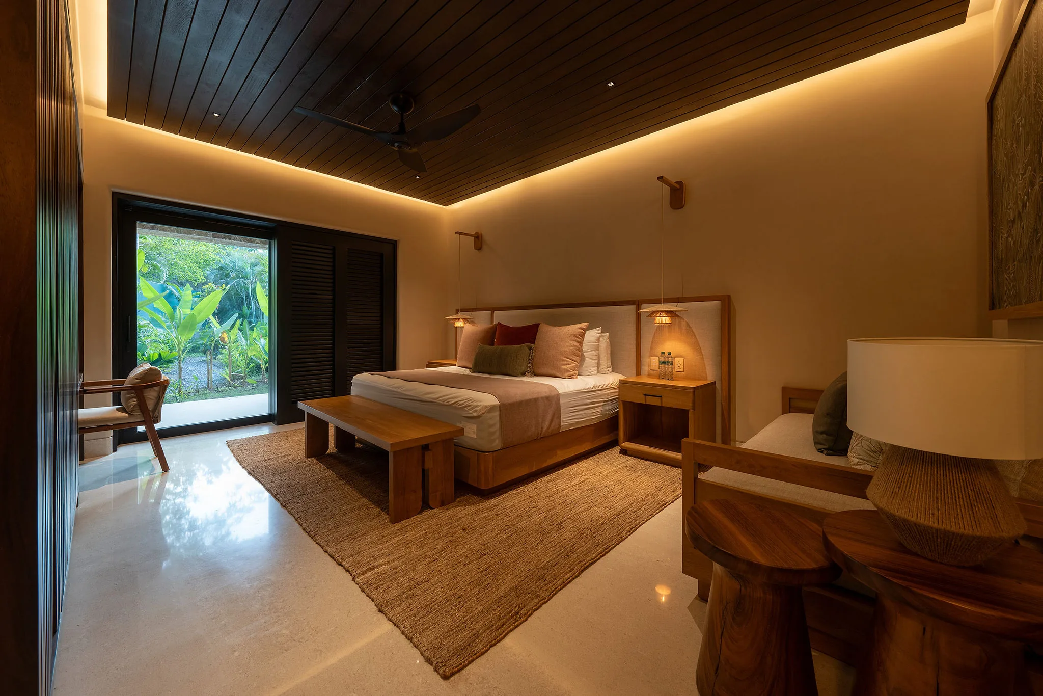 Modern bedroom at Casa Happy Paws, Punta Mita: warm lighting, plush bed, wood accents, sliding doors to lush Ranchos Estates views.