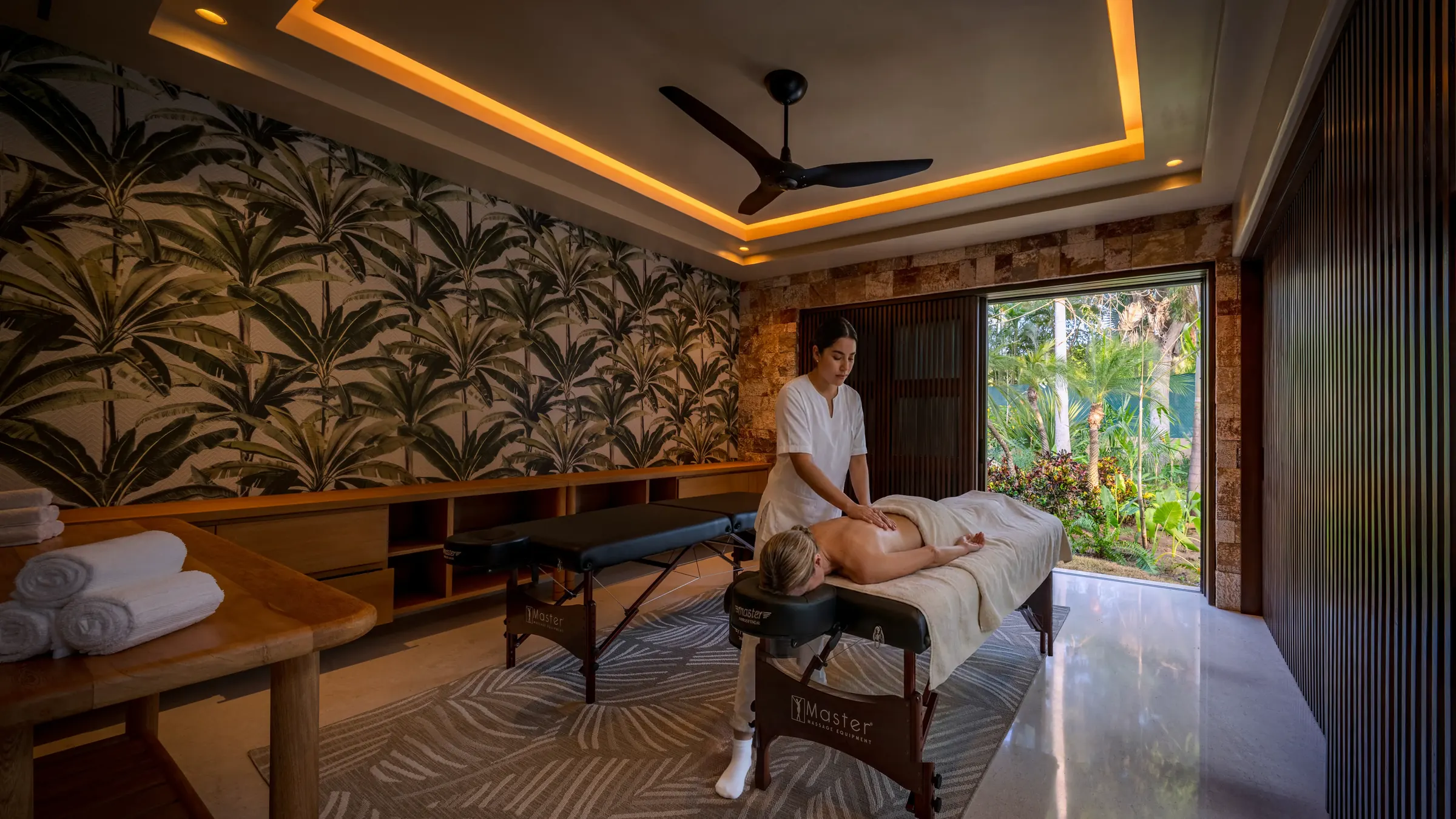 Massage therapist at Casa Happy Paws in Punta Mita, Ranchos Estates, massages client in a tropical room with garden views.