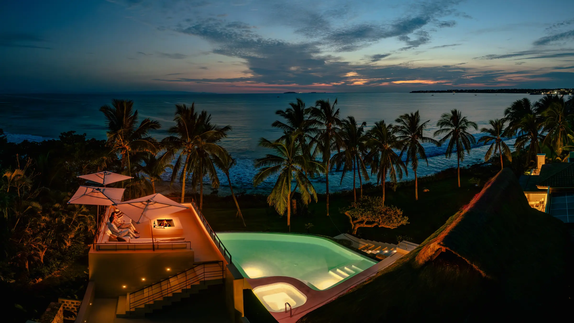 Casa Happy Paws, Punta Mita: Couple and pets relax by the glowing pool at sunset, ocean views, palm trees nearby.