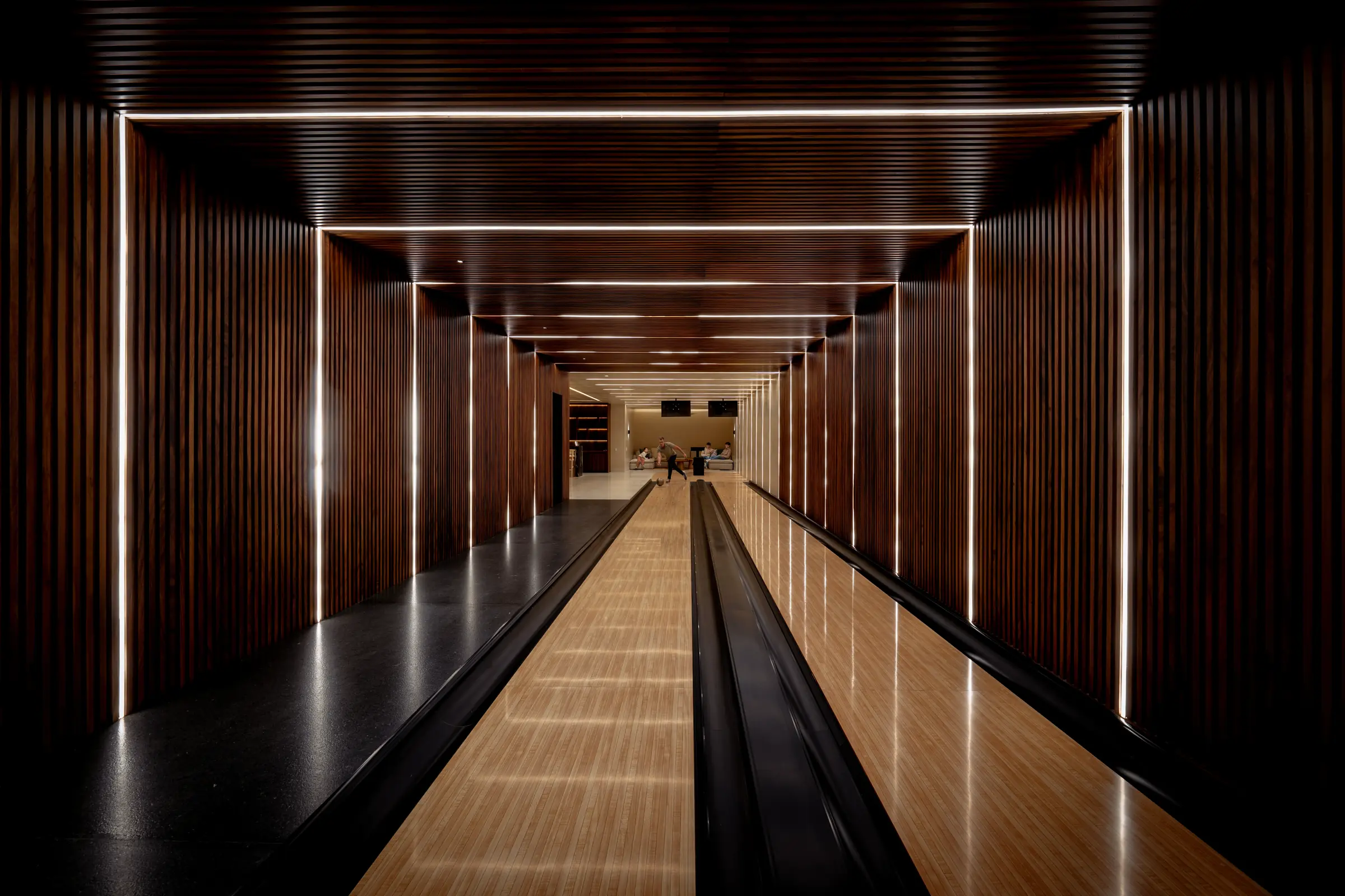Sleek Punta Mita bowling alley in Ranchos Estates with wood lanes, glowing walls; guests enjoying before Casa Happy Paws.