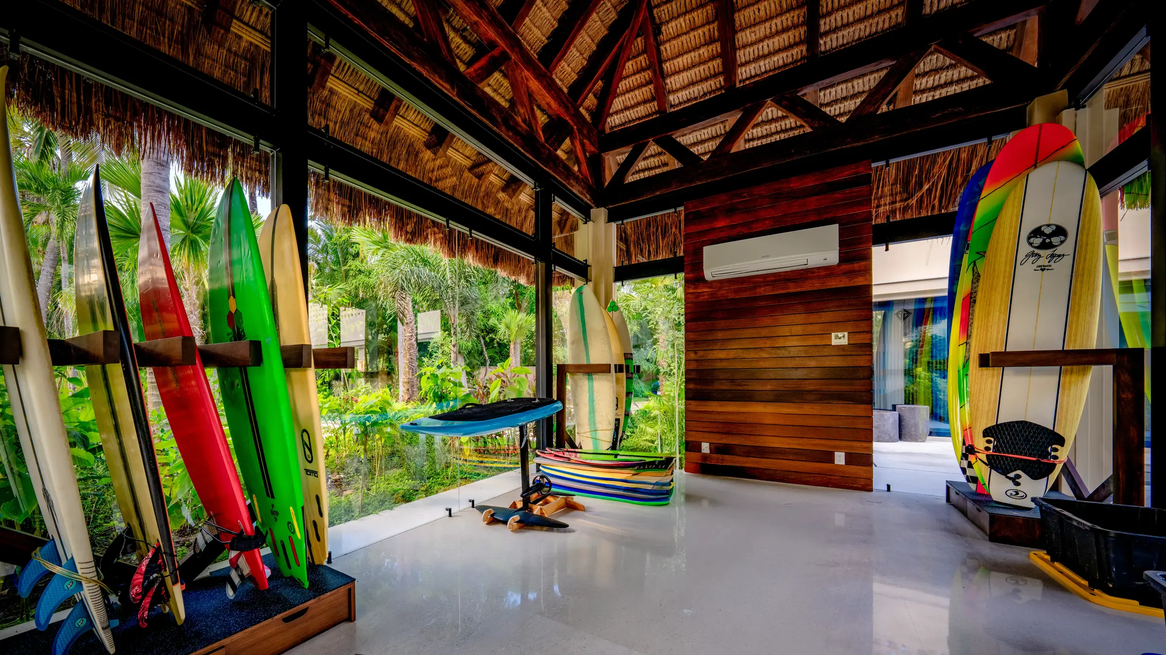 Tropical room in Casa Happy Paws, Ranchos Estates, Punta Mita; wood walls, large windows, surfboards, lush greenery outside.